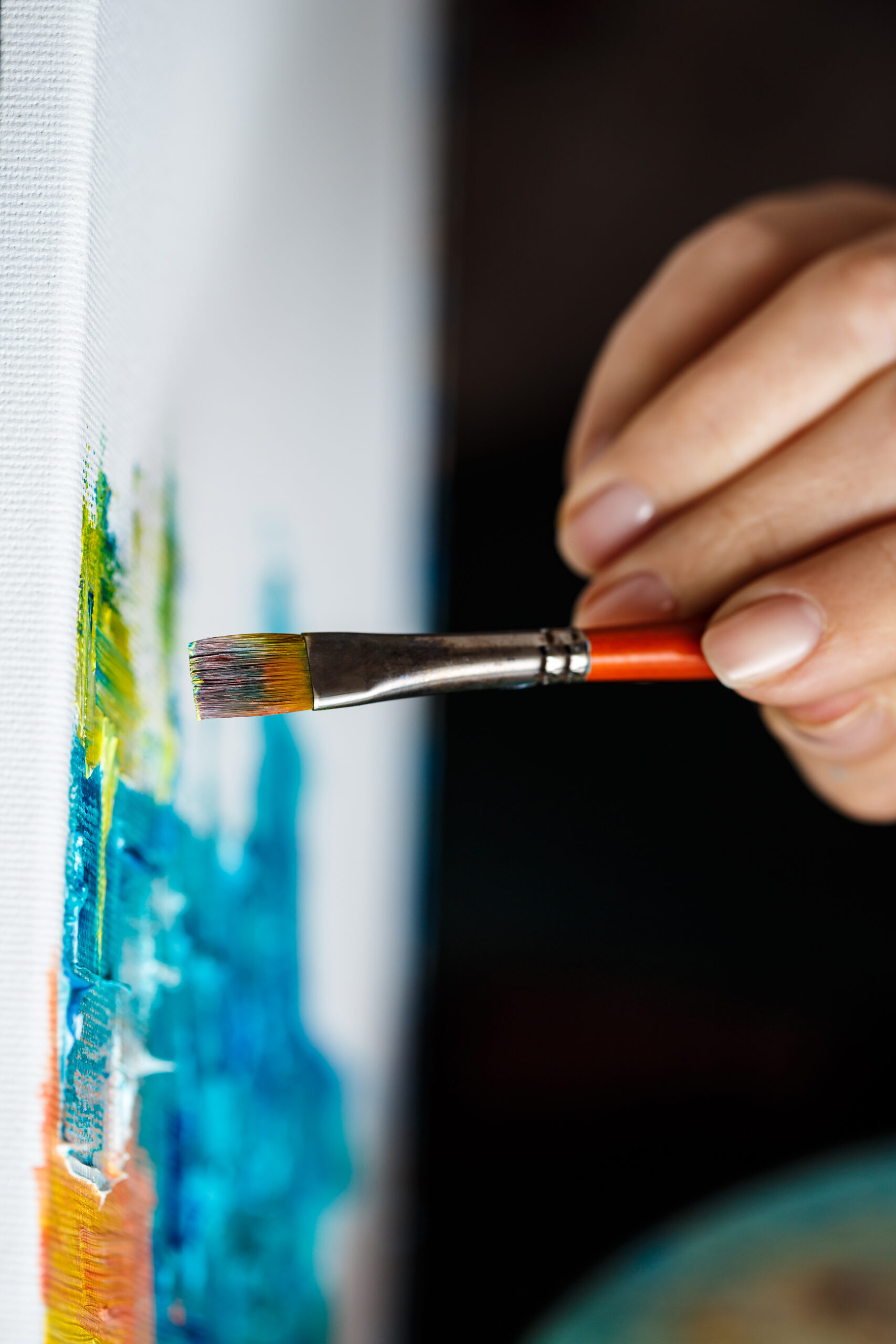 Close up of girl drawing with oil paints on canvas.